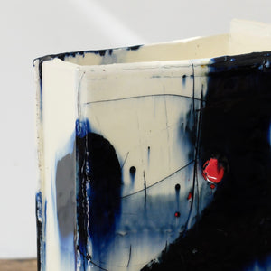 Detail of ceramics vessel in white with navy blue and red painterly marks